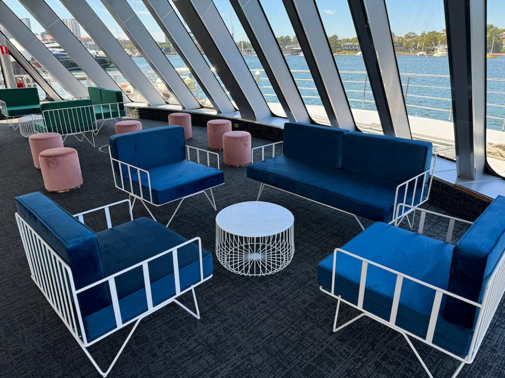 navy blue velvet wire arm chair with white wire coffee table on a boat